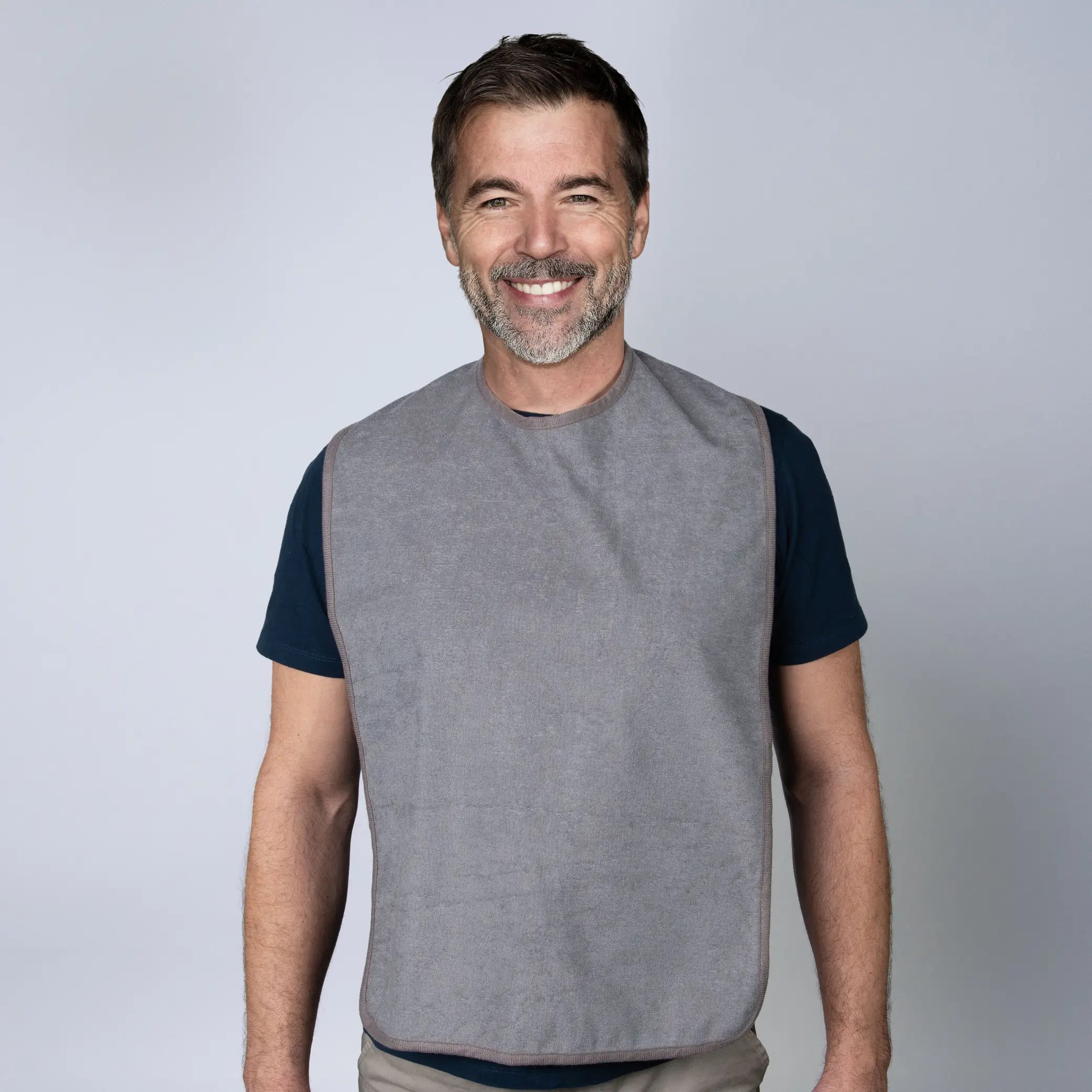 Man wearing a StayDry absorbent and waterproof clothing protector in grey, designed for adults and seniors. This full-coverage adult bib features a soft, absorbent front and a waterproof backing to protect against food spills, stains and liquids during meals.