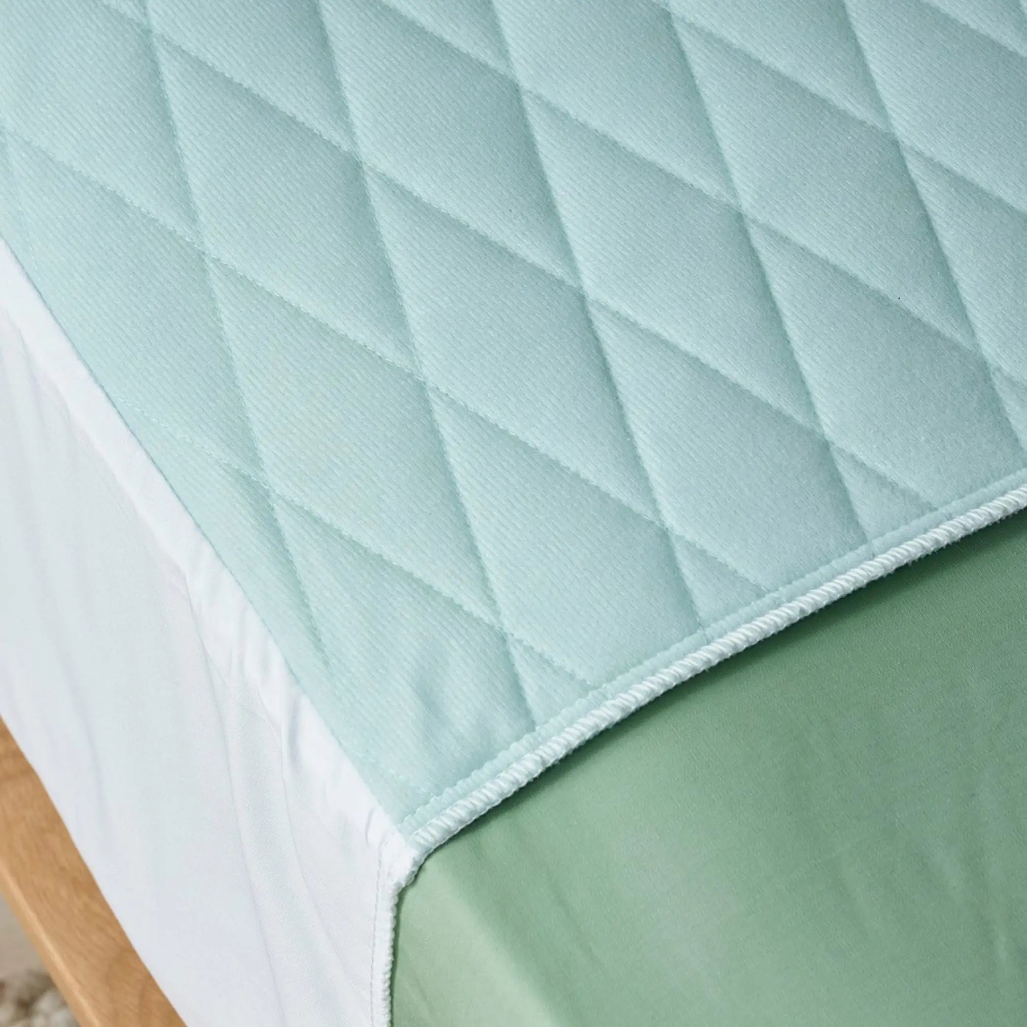 Close-up view of a quilted blue waterproof bed pad designed for incontinence protection. Featuring a soft, absorbent, and breathable fabric with a secure fit.