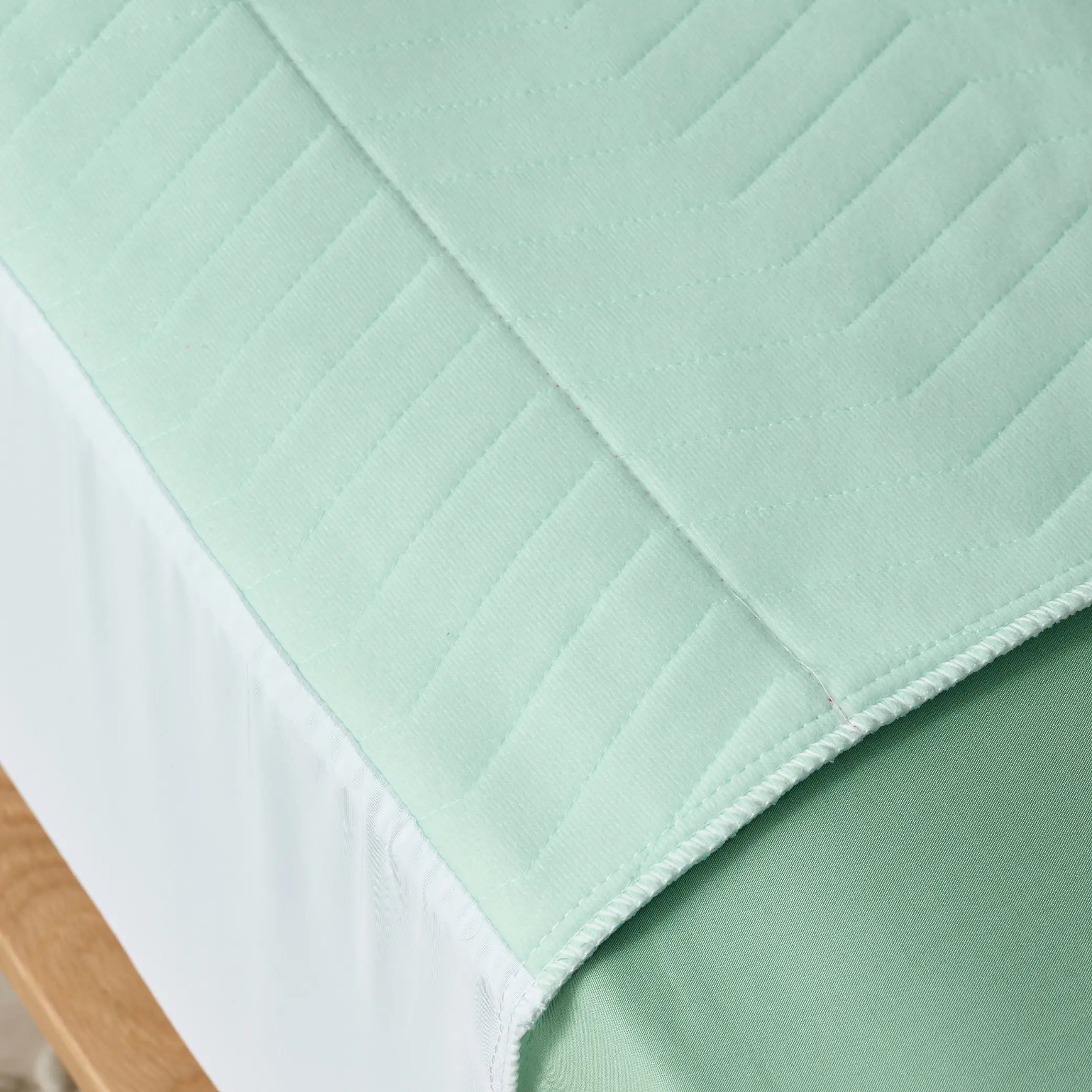 Close-up of the Boss Waterproof Bed Pad in sage green, showing its soft, quilted texture and high-absorbency layers. Designed for incontinence protection, this reusable and washable bed pad ensures mattress dryness while providing breathable comfort.