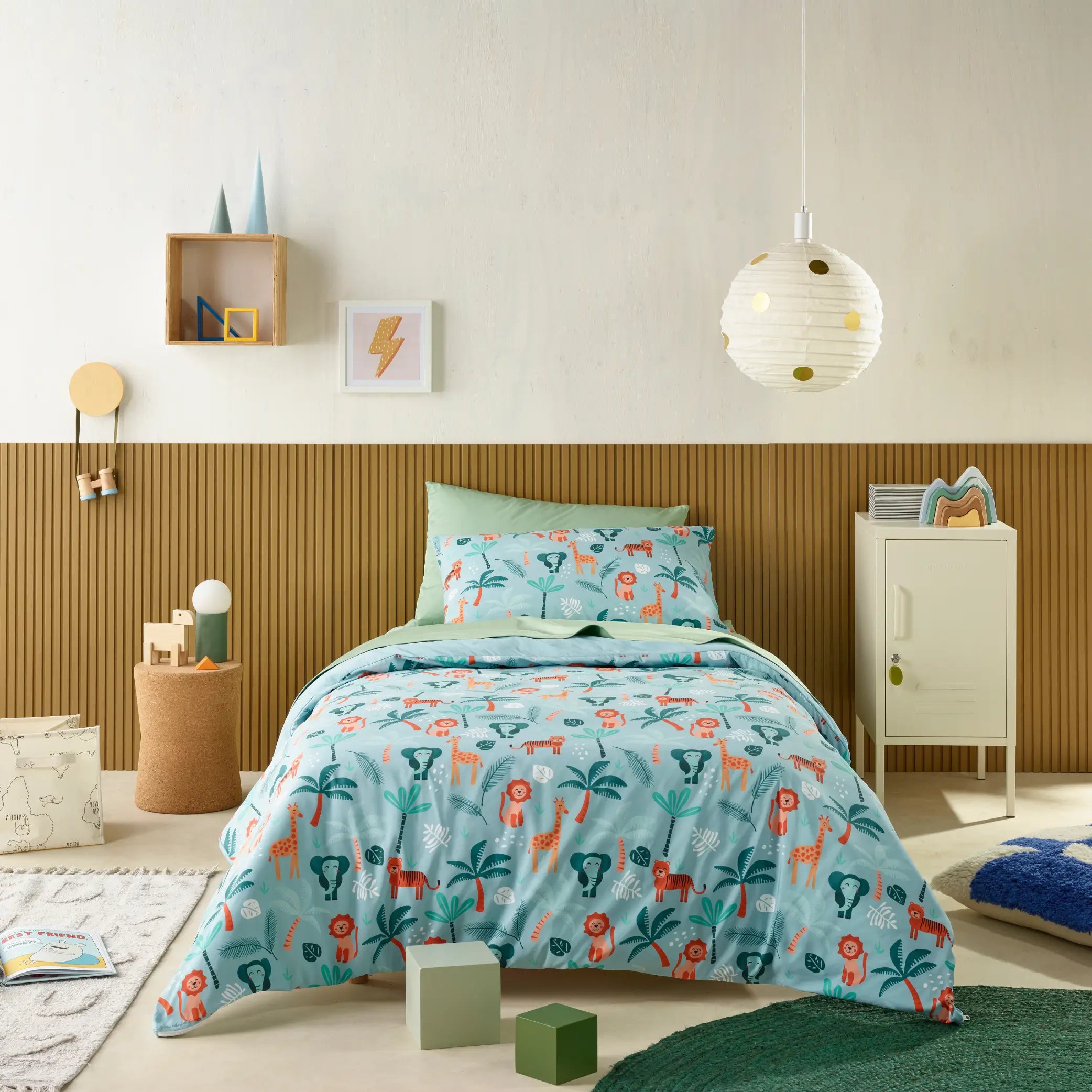 Kids' bedroom featuring a water-resistant quilt cover set with a fun jungle animal theme. The bedding showcases playful lions, giraffes, elephants, and lush green palm trees on a soft aqua background, creating a vibrant and adventurous look