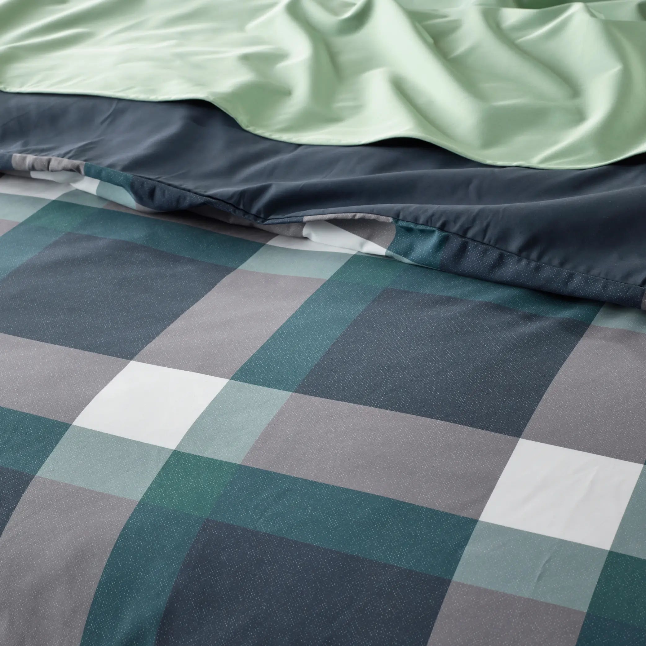 Close-up of a water-resistant quilt cover set featuring a forest green, navy blue, and grey checkered pattern