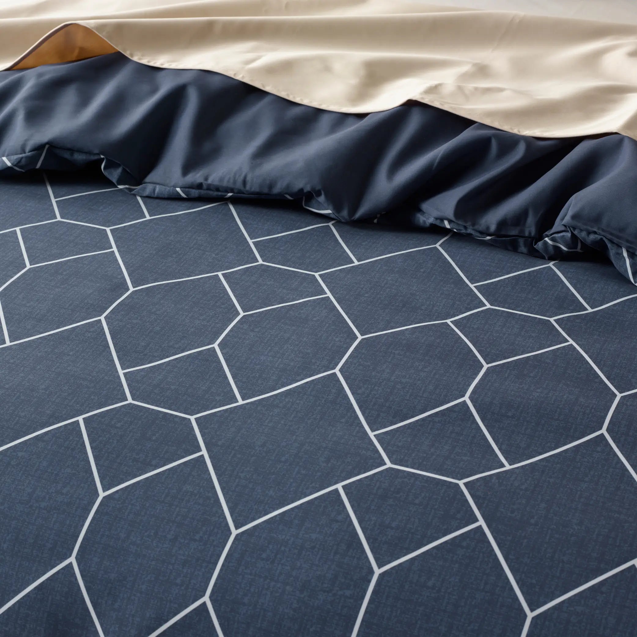 Close-up of a navy blue geometric waterproof quilt cover featuring a modern white hexagonal pattern. 