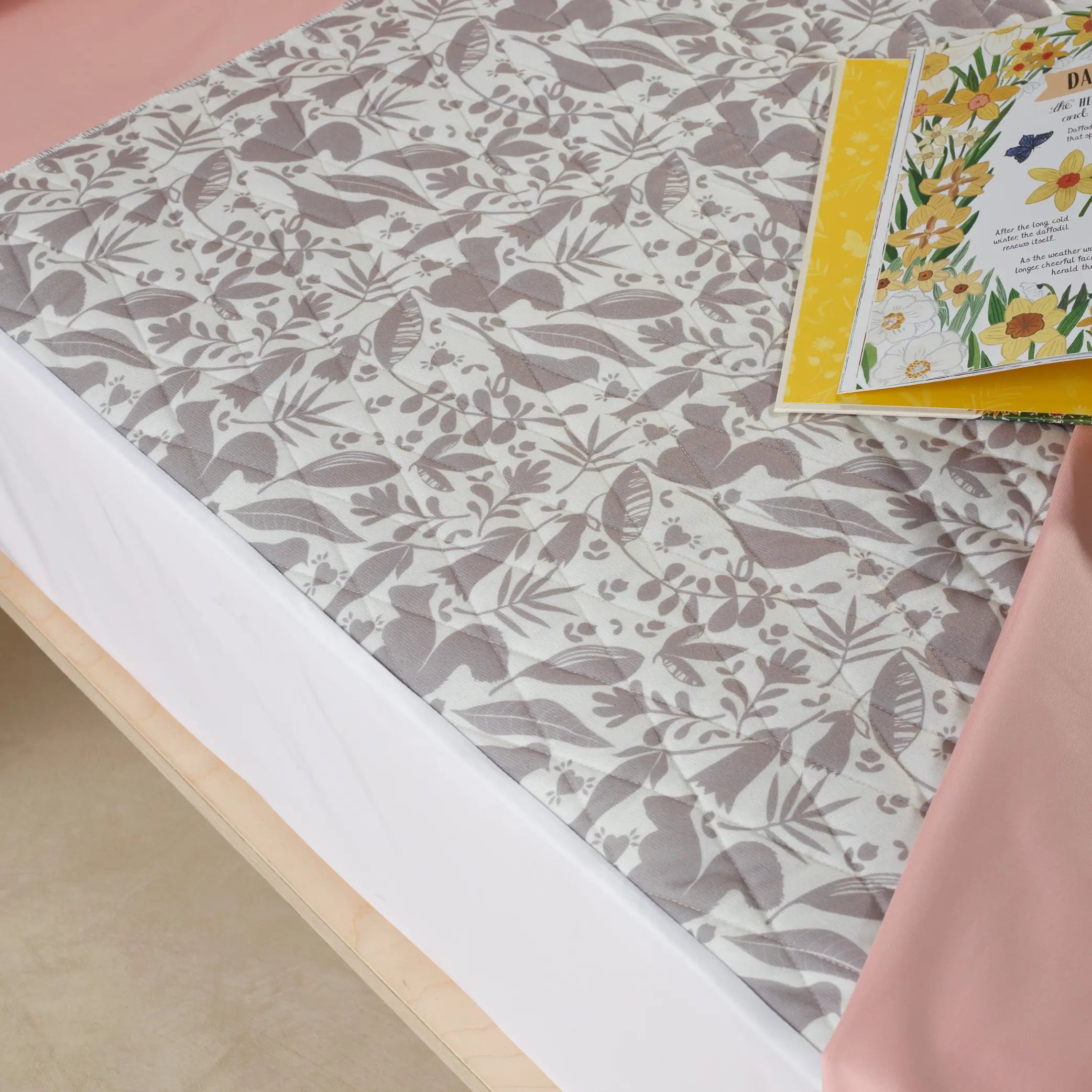 Close-up of a children's waterproof absorbent bed pad featuring a soft, nature-inspired printed design. This reusable, washable incontinence pad offers leak-proof mattress protection, ideal for toilet training and night-time accidents.