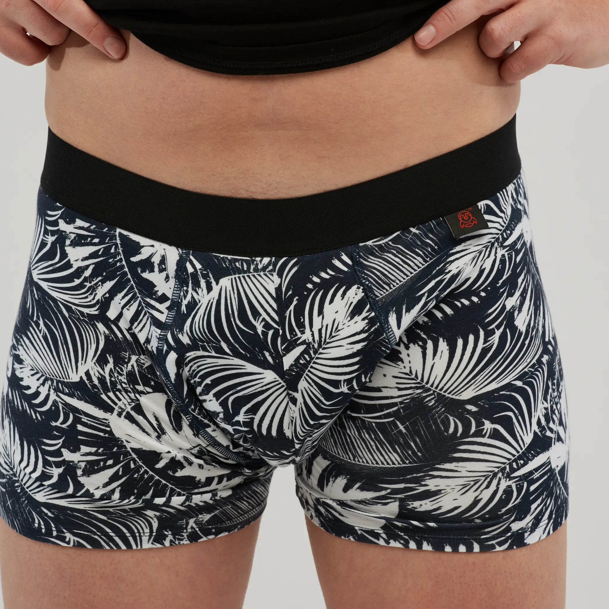 Close-up of StayDry men's waterproof incontinence trunks featuring a black and white tropical print. These absorbent boxer briefs provide discreet leak protection with a secure waistband and stylish design.