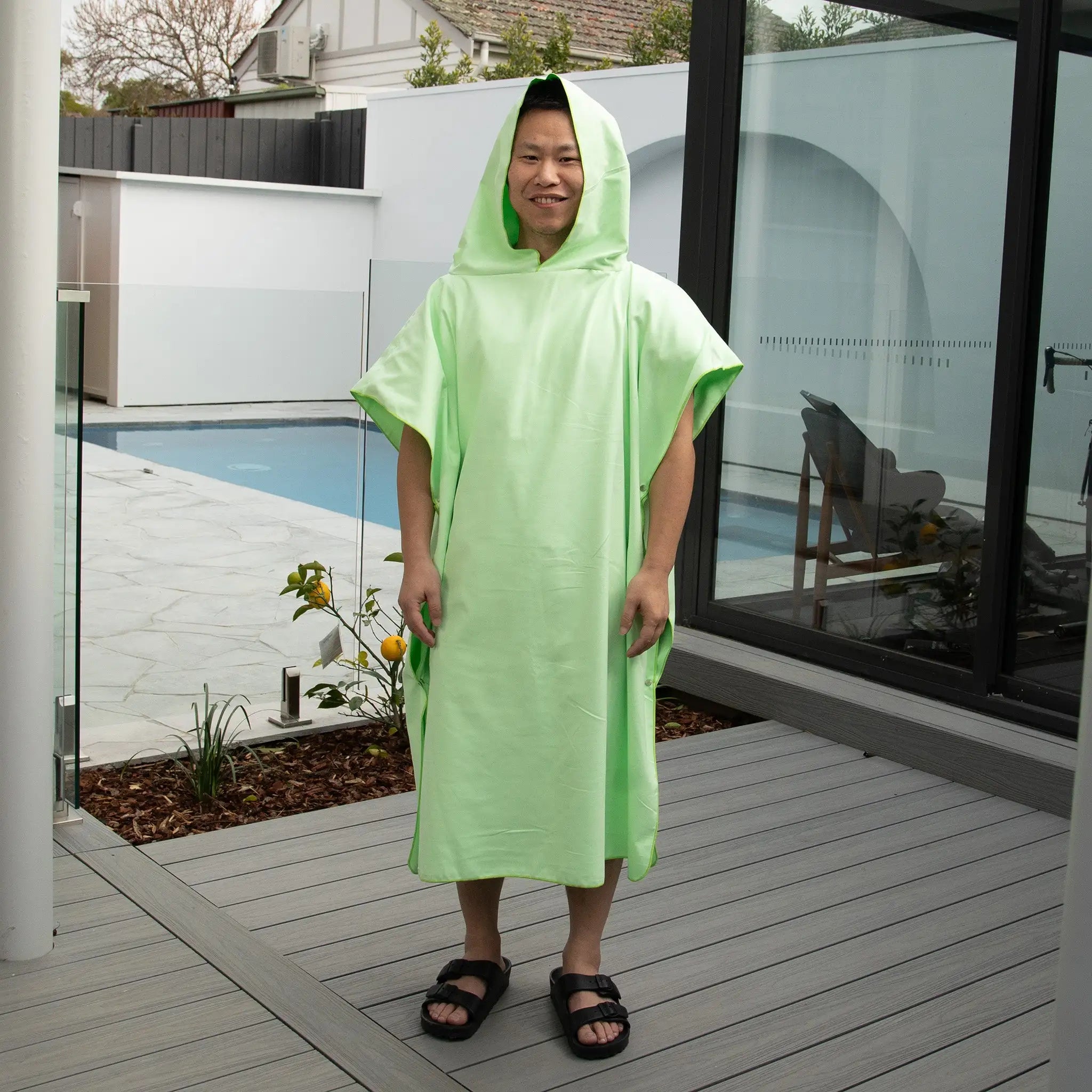 Man wearing StayDry microfibre hooded poncho towel in light green, perfect for quick-drying after swimming, beach or shower use.