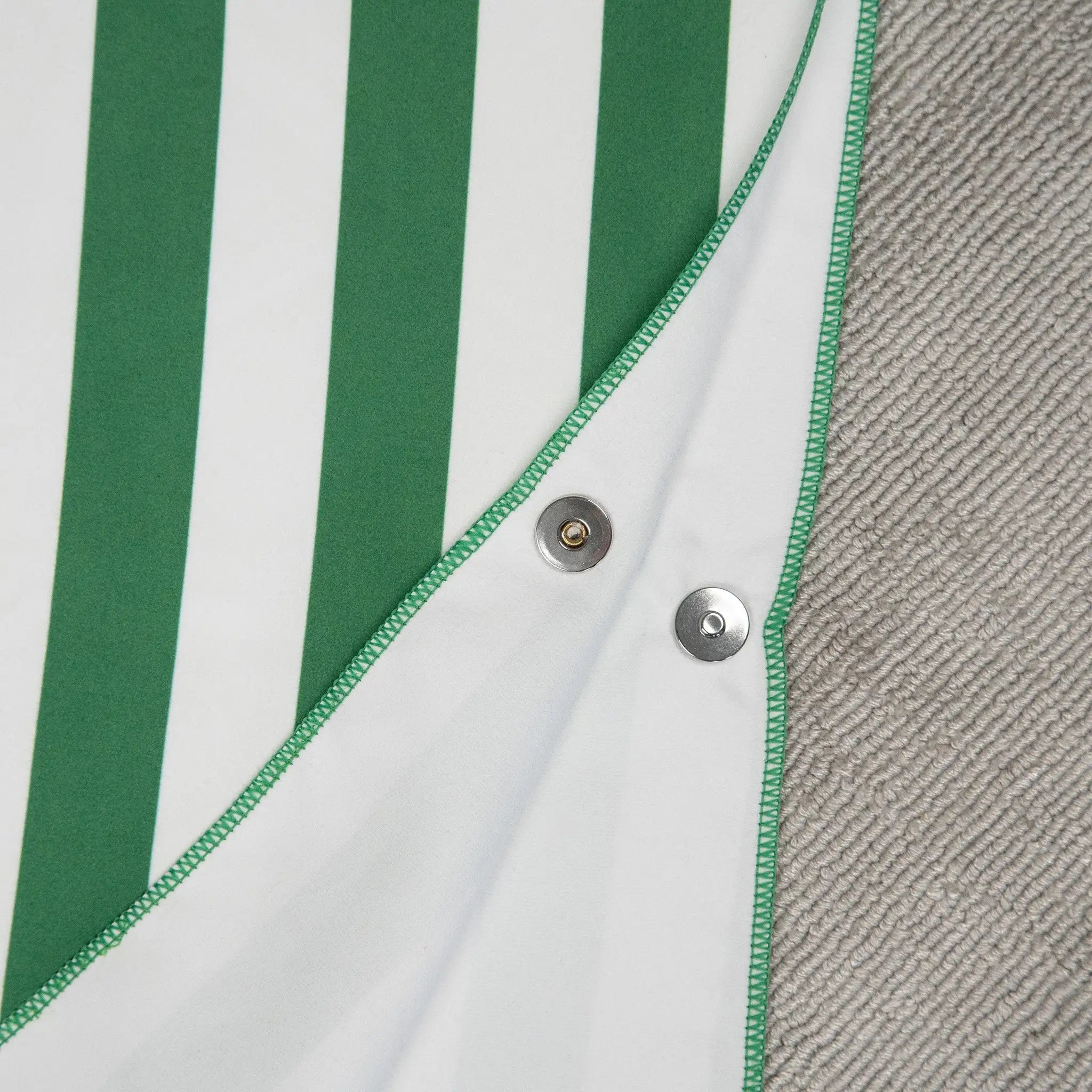 Close-up of StayDry microfibre poncho towel for kids in green and white stripes, featuring secure snap button closures for easy wear and adjustable fit.