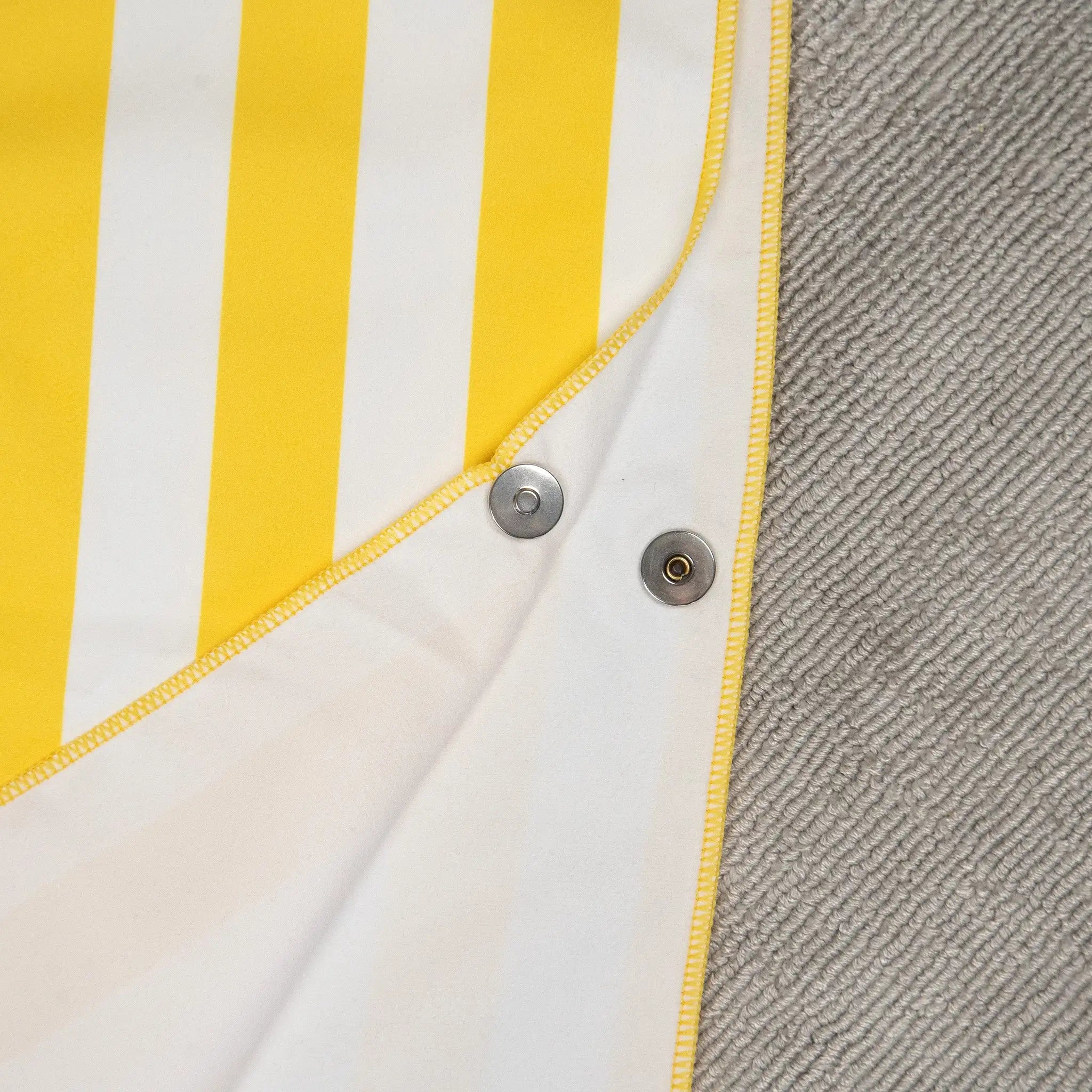 Close-up of StayDry microfibre poncho towel in yellow and white stripes, showing snap buttons and reinforced stitching. Lightweight, ultra-absorbent, and fast-drying towel for kids.