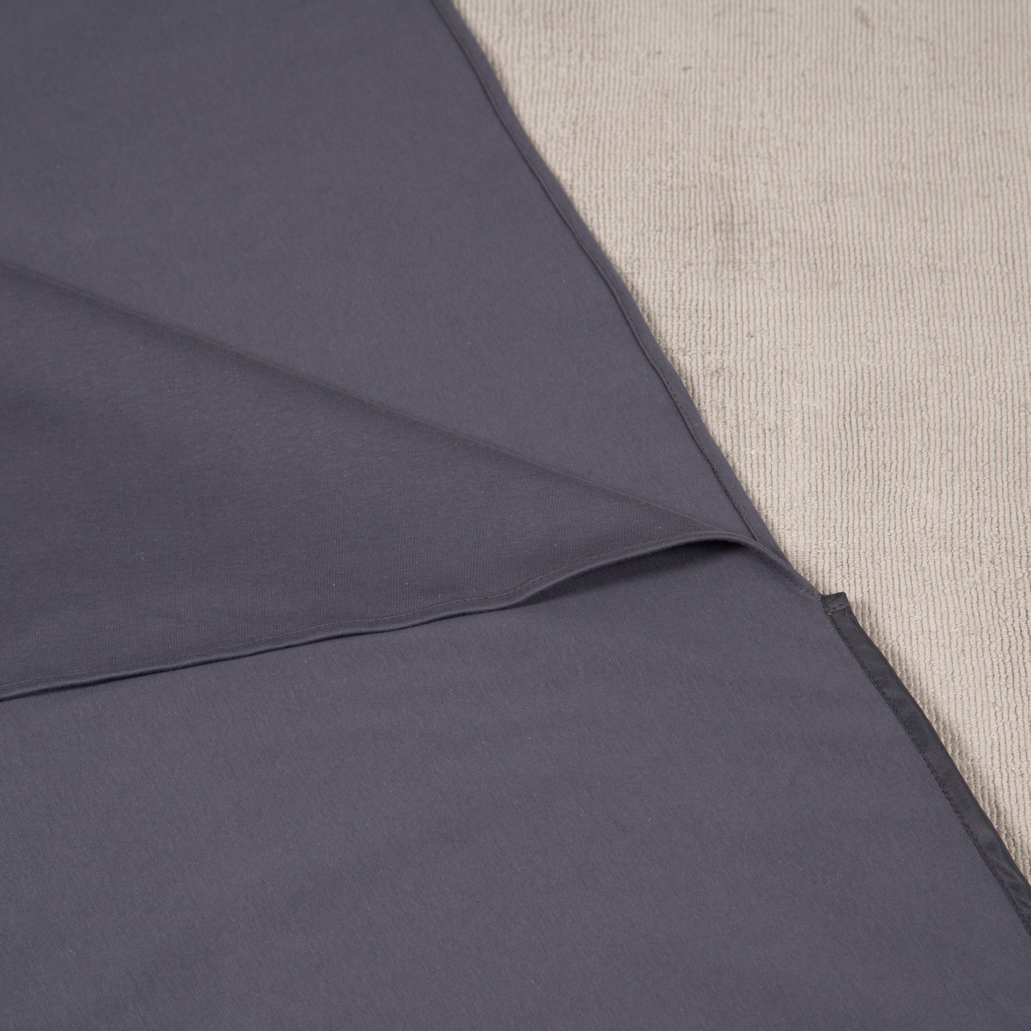 Close-up of a grey waterproof and absorbent sleeping bag liner, showcasing its soft fabric top layer and neatly stitched edges. Designed for camping, travel and incontinence protection.