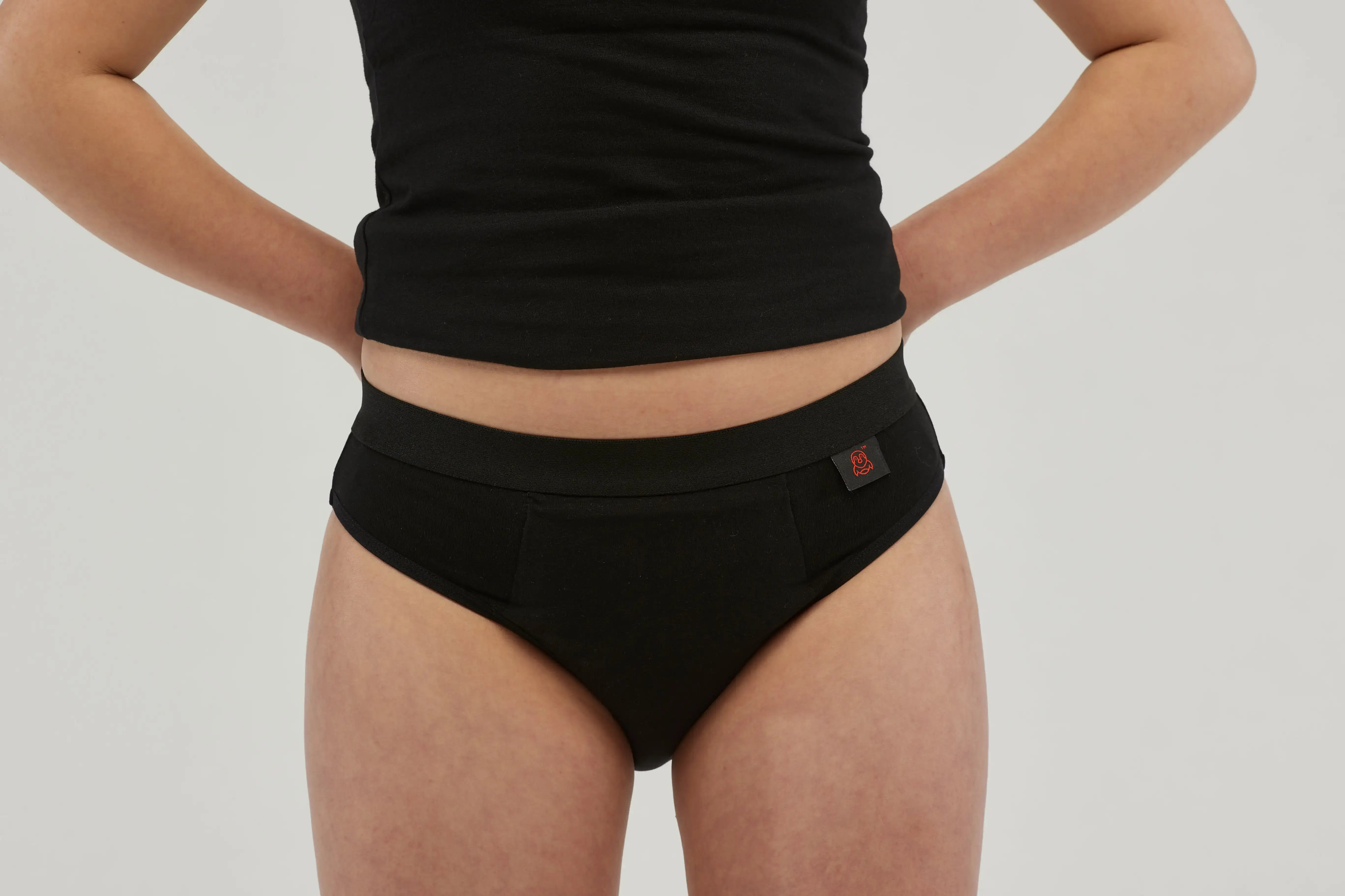 Front view of teen girls' black incontinence underwear featuring a discreet, absorbent core and leak-proof protection. Made from breathable, moisture-wicking fabric, these machine-washable, reusable briefs provide all-day comfort and security