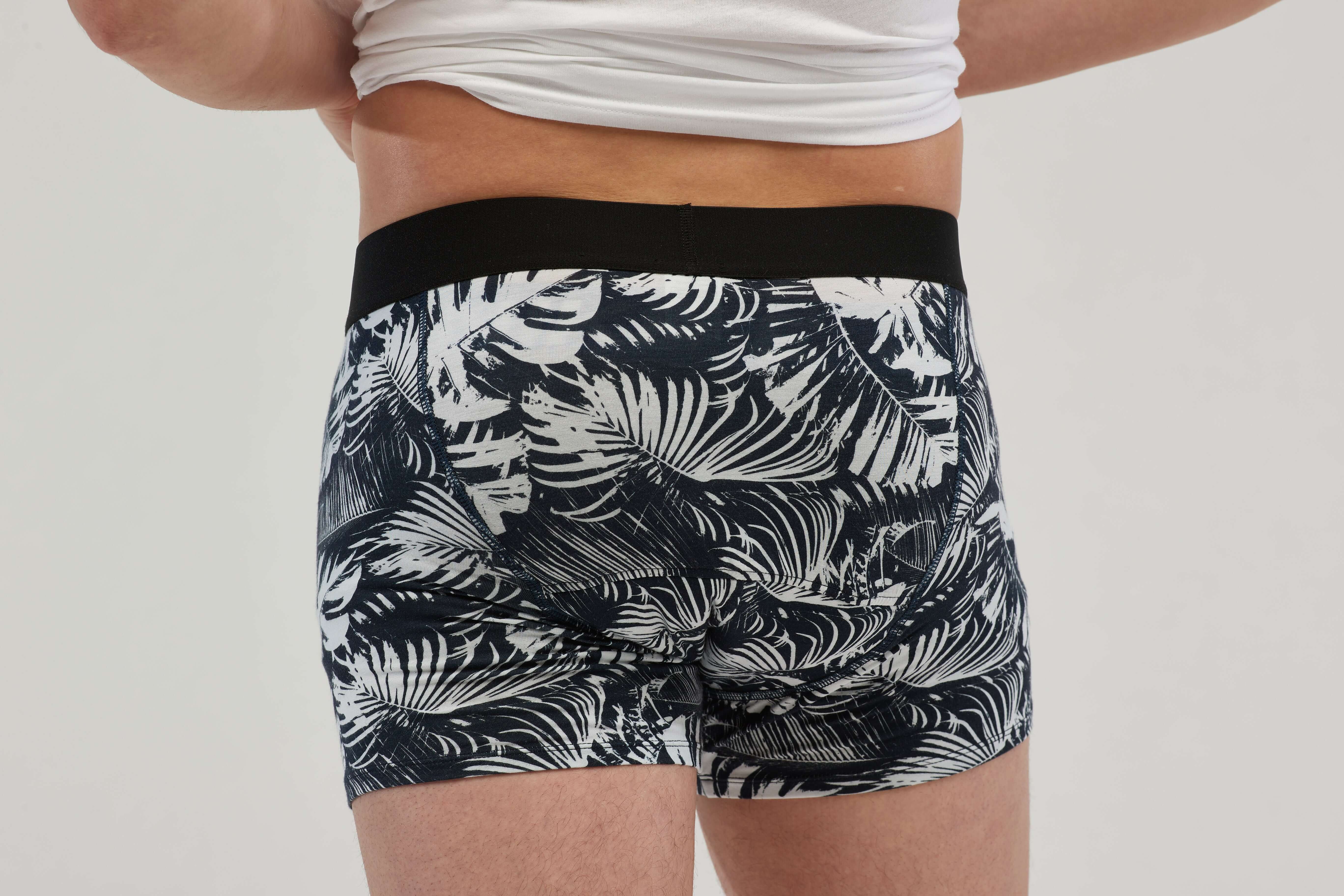 Rear view of teen boys' incontinence boxer briefs with a black and white tropical palm leaf print. Featuring a discreet, absorbent core and leak-proof protection, these moisture-wicking, breathable underwear provide all-day comfort and confidence. Designed with a secure elastic waistband and a snug yet flexible fit, these machine-washable boxers are ideal for active lifestyles.