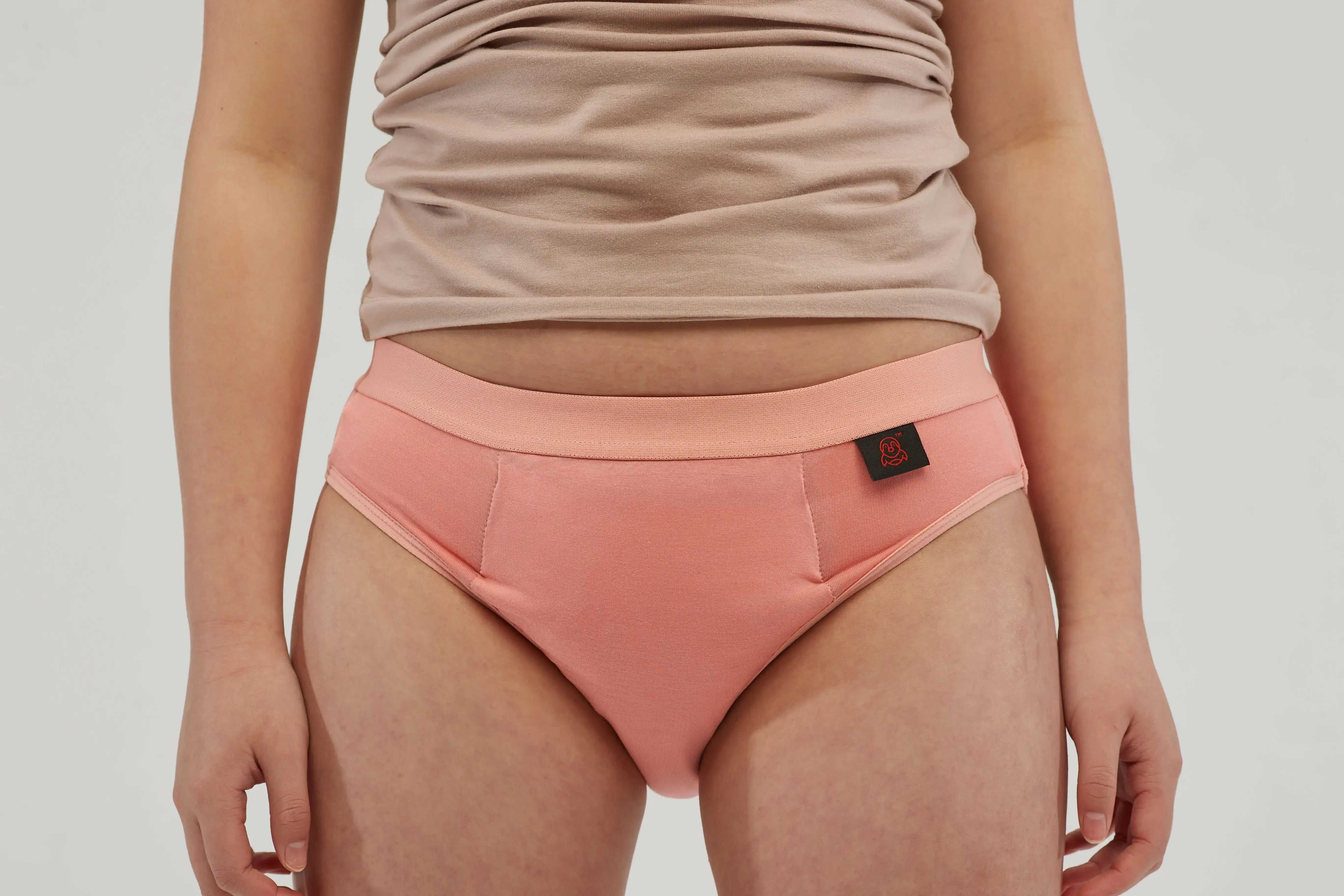 Close-up of teen girls' incontinence underwear in soft peach pink, featuring a discreet absorbent core and leak-proof protection. Designed with a breathable, moisture-wicking fabric and a secure elastic waistband for all-day comfort and confidence. These machine-washable, reusable briefs provide a stylish and practical alternative to traditional incontinence products, perfect for active lifestyles.