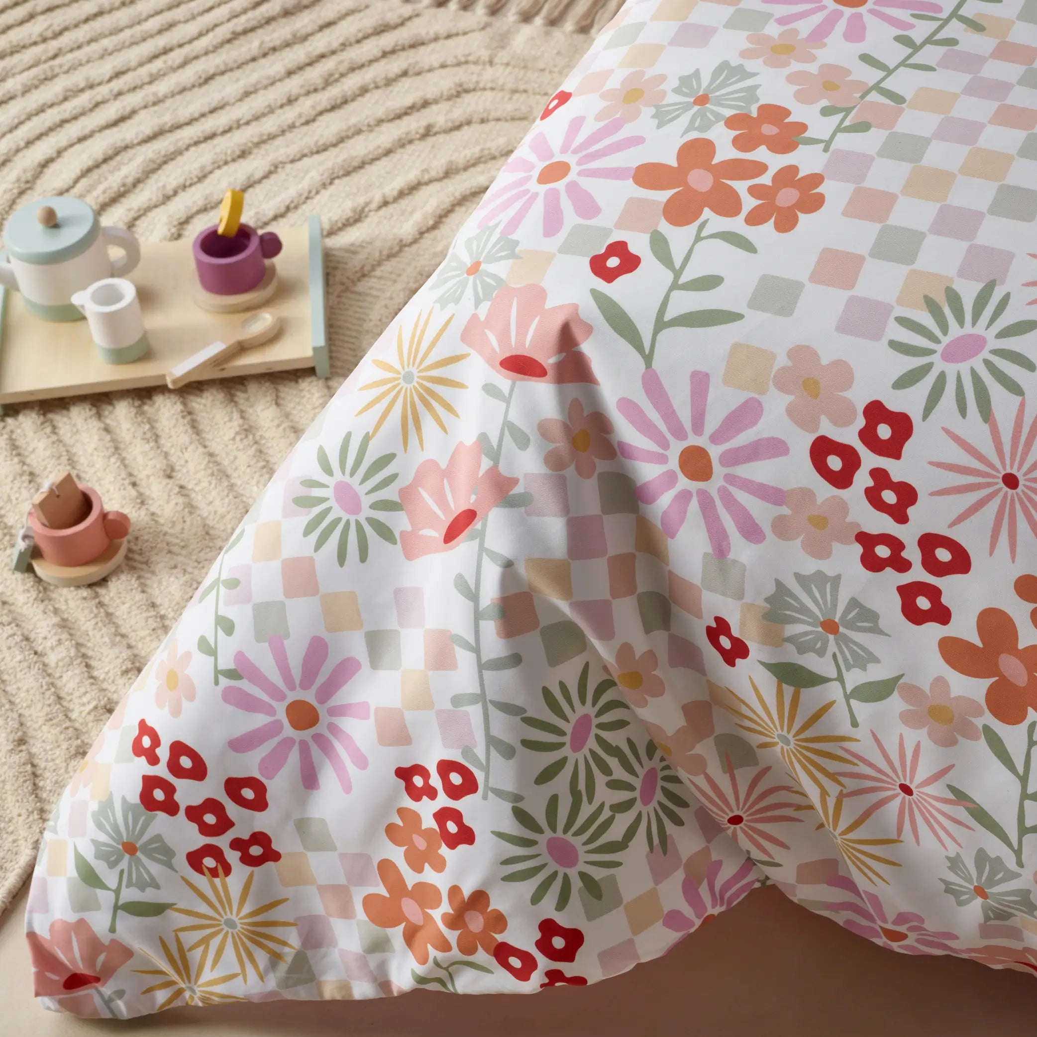 Kids' waterproof quilt cover featuring a vibrant floral 'Blooms' design with colourful flowers and a pastel checkered pattern. Made from breathable, moisture-resistant fabric this durable and machine-washable bedding provides incontinence protection while adding a playful and stylish touch to children's bedrooms. Perfect for easy-care and mess-free sleeping.