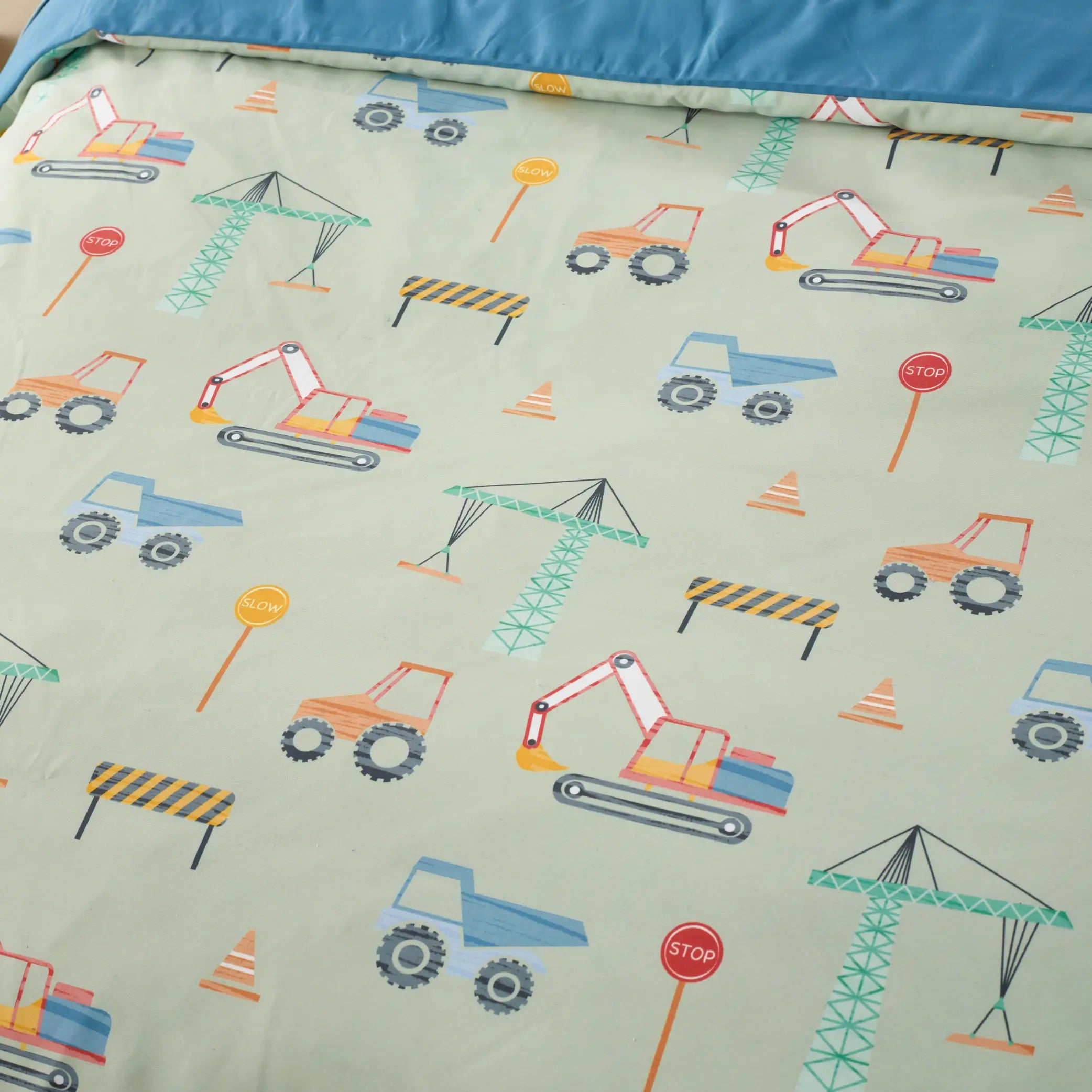 Close-up of a kids' waterproof quilt cover featuring a fun construction-themed pattern with excavators, dump trucks, cranes, stop signs, and traffic cones on a soft sage green background. Made from moisture-resistant, breathable fabric, this durable and machine-washable bedding provides incontinence protection.