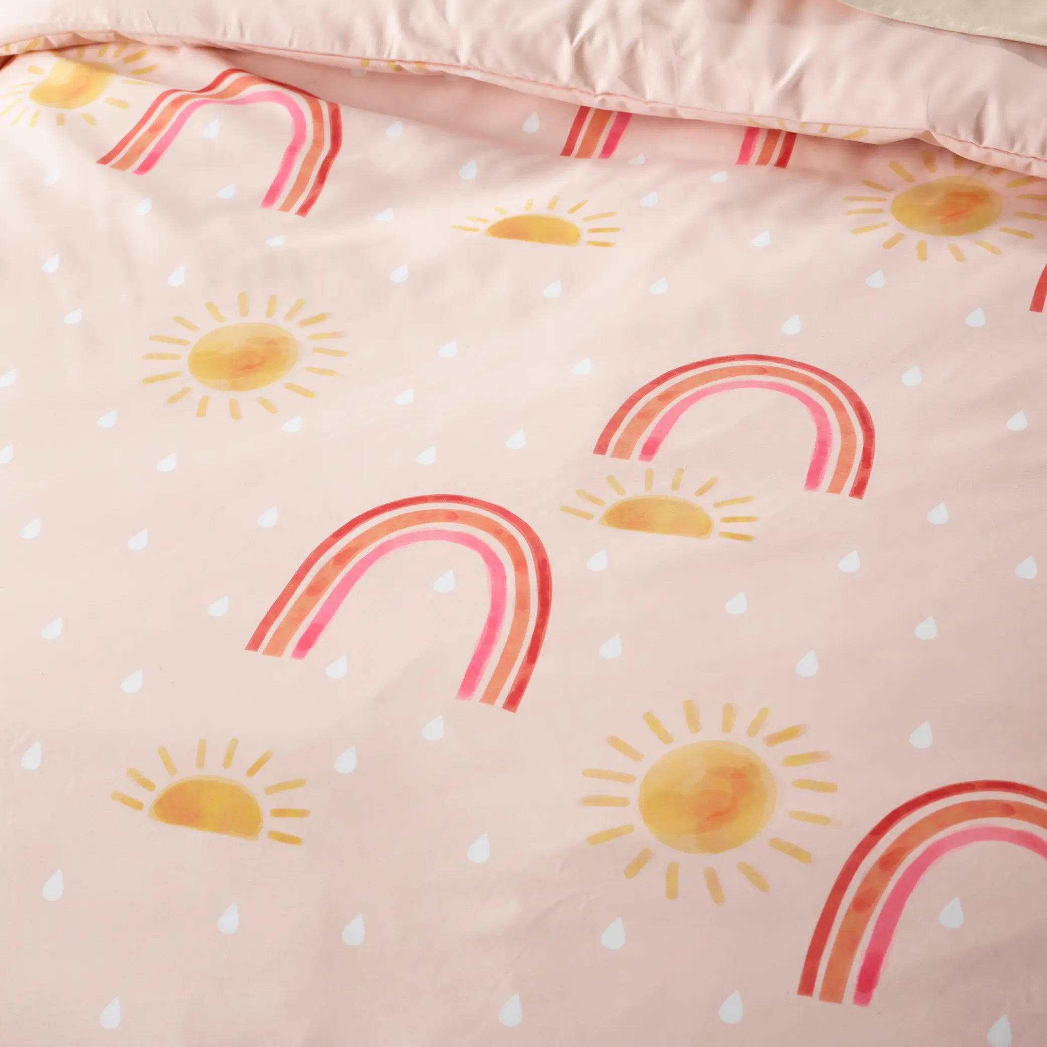 Close-up of a kids' waterproof quilt cover featuring a cheerful pink design with hand-painted rainbows, sunshine, and raindrops. Made from breathable, moisture-resistant fabric, this durable and machine-washable bedding provides incontinence protection while adding a bright and uplifting touch to children's bedrooms. Ideal for easy-care and mess-free sleeping.