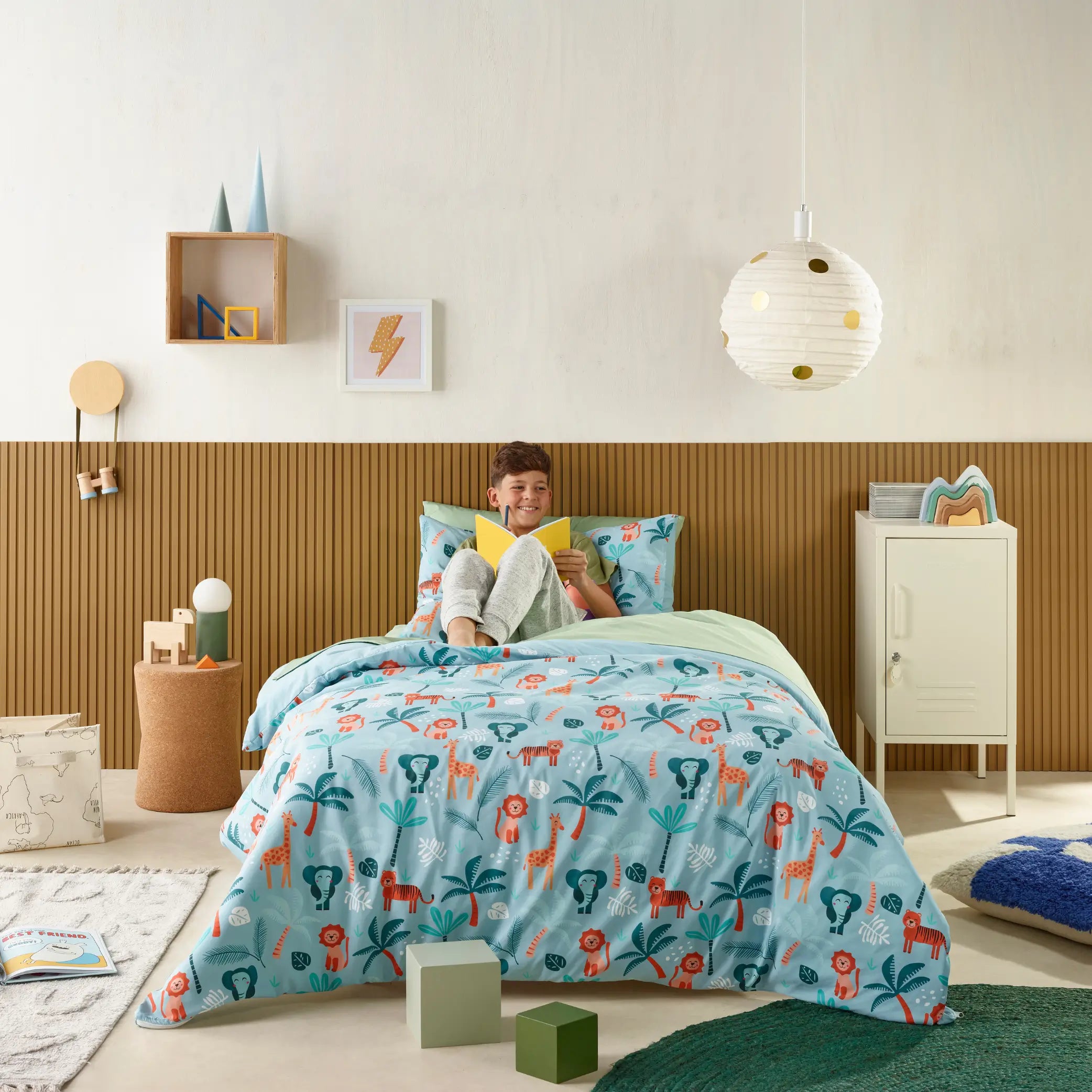 Kids' waterproof quilt cover with a playful jungle explorer theme, featuring lions, tigers, giraffes, and tropical trees on a soft blue background. Made from breathable, moisture-resistant fabric, this durable bedding set provides incontinence protection while ensuring a cosy and comfortable night's sleep. Ideal for children who need extra bed protection, this machine-washable and hypoallergenic quilt cover.