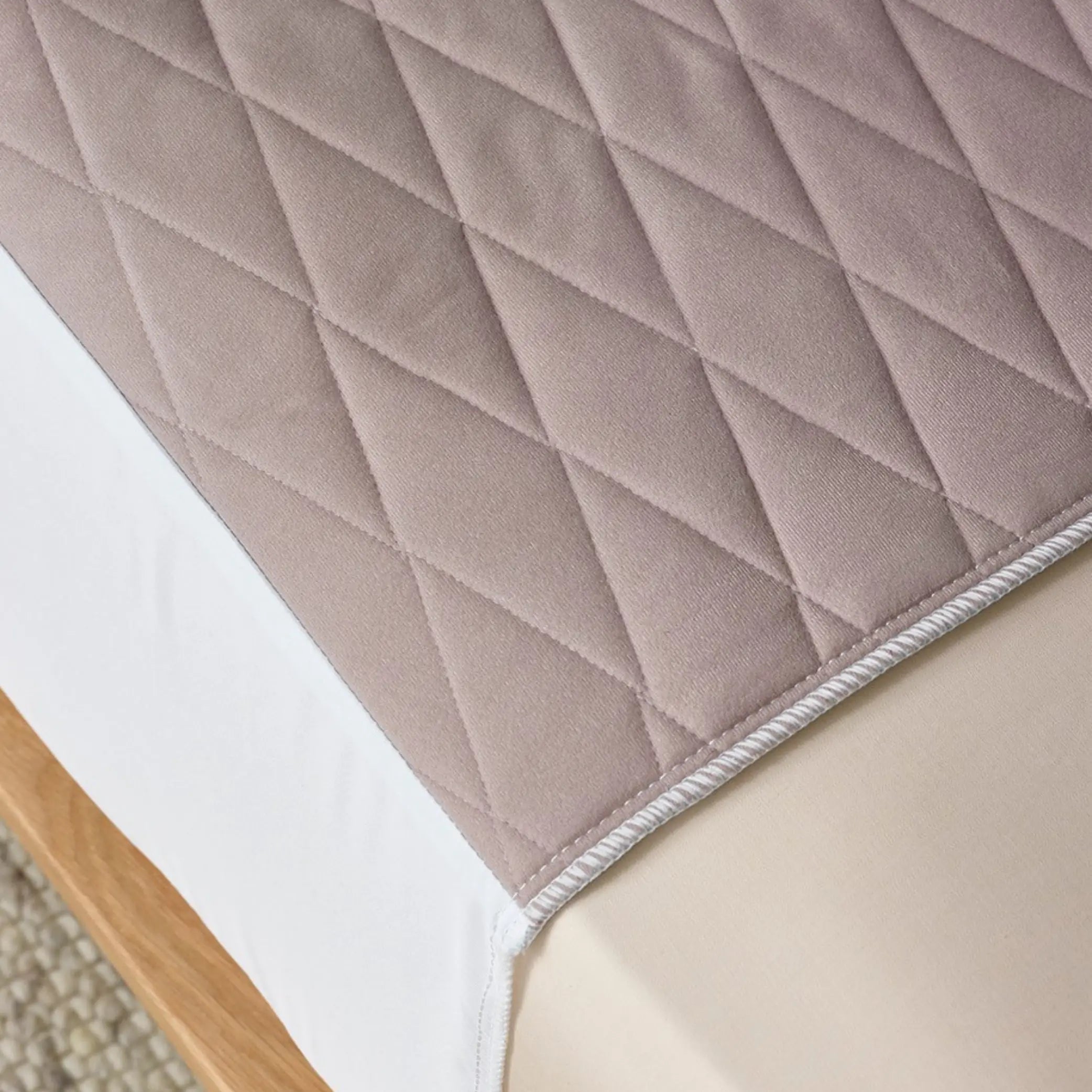 Close-up of a clay-coloured quilted waterproof bed pad, designed for incontinence protection. Made from soft, breathable, and absorbent fabric with a secure fit to keep bedding dry and comfortable.