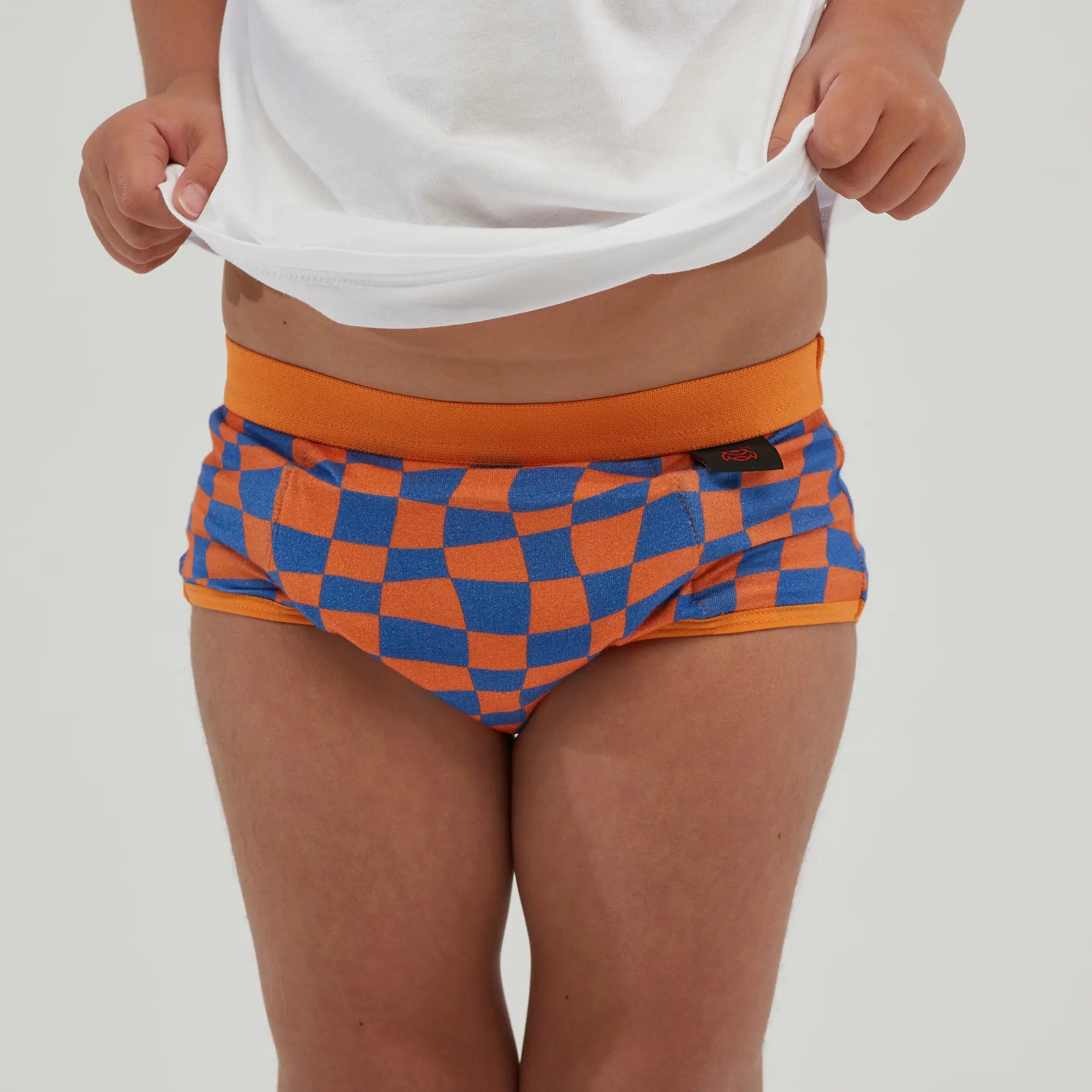 children's incontinence underwear in a vibrant orange and blue checkered design, featuring a discreet absorbent core for leak-proof protection. Made from breathable, moisture-wicking fabric, these reusable, machine-washable undies provide all-day comfort and security.