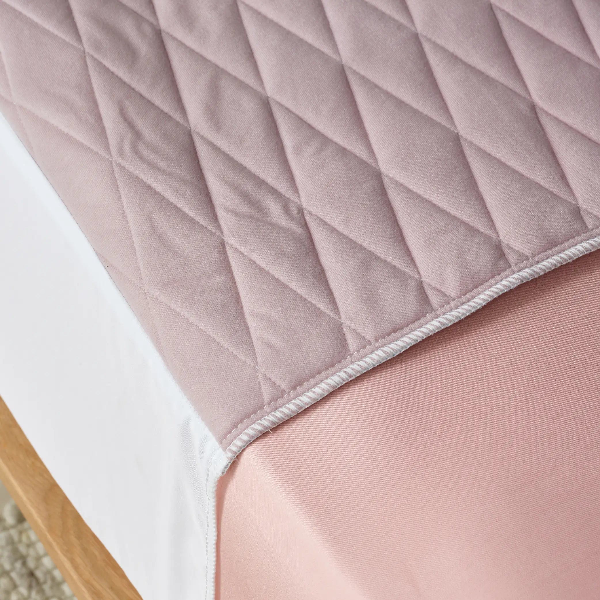 Close-up of a lilac waterproof bed pad with a quilted, soft-touch surface. This incontinence bed protector is absorbent, washable, and designed to keep bedding dry and comfortable.