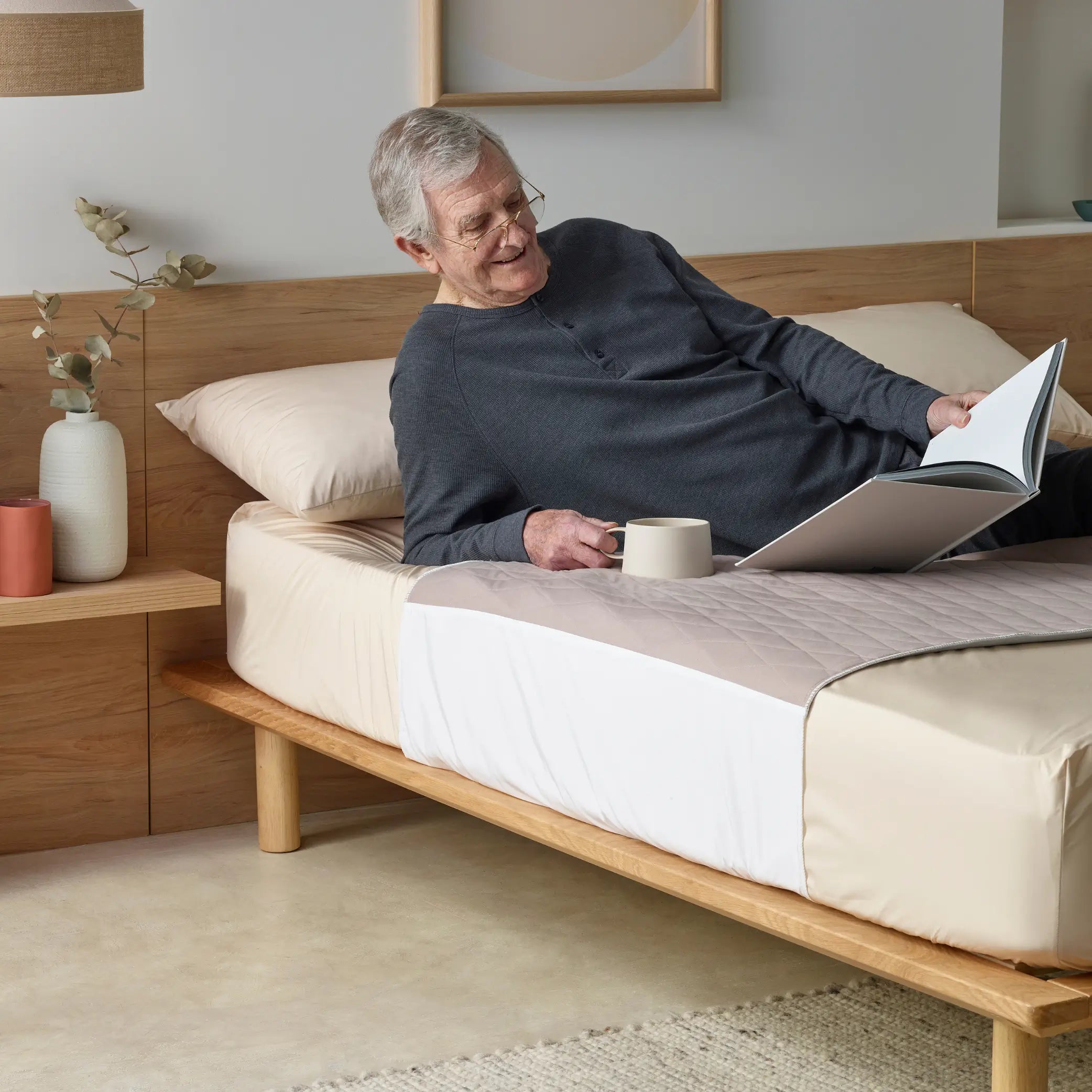 Elderly man relaxing on a bed with a quilted waterproof bed pad in clay colour. Designed for incontinence protection, this absorbent, breathable, and washable bed pad keeps bedding dry and comfortable.